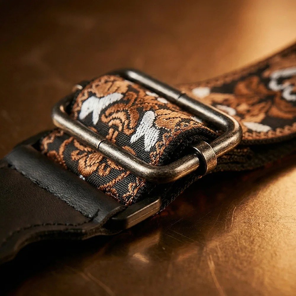 Gros plan sur la boucle de réglage en métal vieilli et le motif tissé cuivre et blanc de la sangle Baroque Bourbon