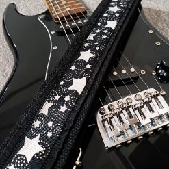 Sangle guitare noire à étoiles argentées Silver Night posée sur une guitare électrique noire