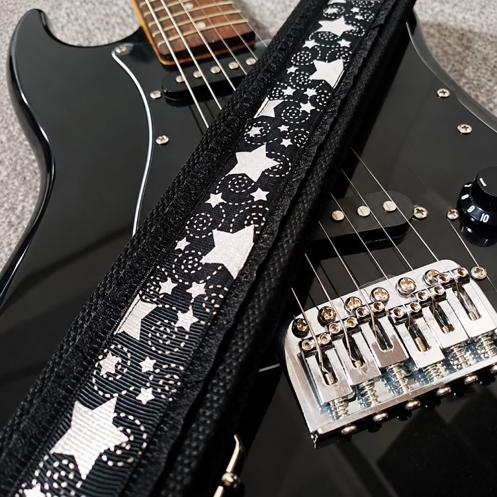 Sangle guitare noire à étoiles argentées Silver Night posée sur une guitare électrique noire
