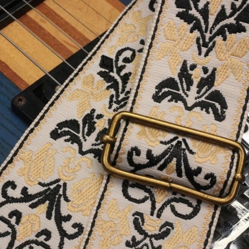 Gros plan du tissage jacquard et de la boucle de réglage bronze de la sangle guitare