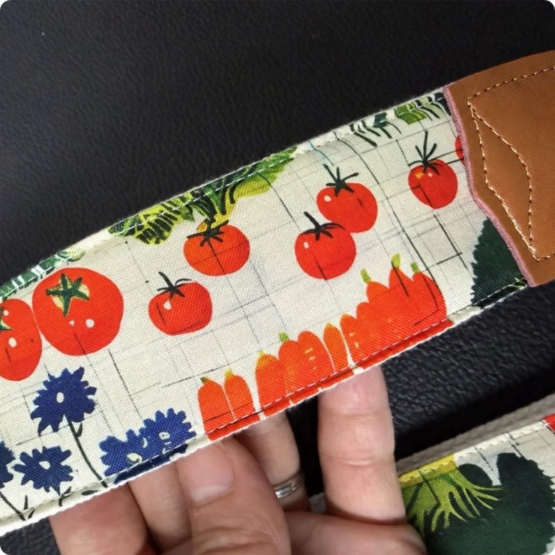 Gros plan du motif tomates, carottes et fleurs bleues de la sangle guitare Jardin du Potager
