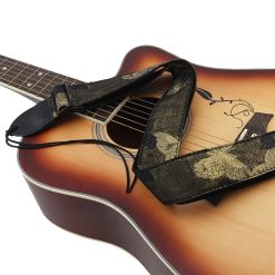 Sangle guitare jacquard noire à papillons dorés Papillon d'Or posée sur une guitare acoustique sunburst