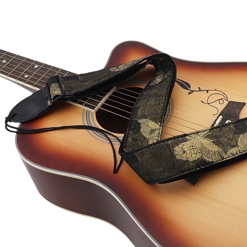 Sangle guitare jacquard noire à papillons dorés Papillon d'Or posée sur une guitare acoustique sunburst