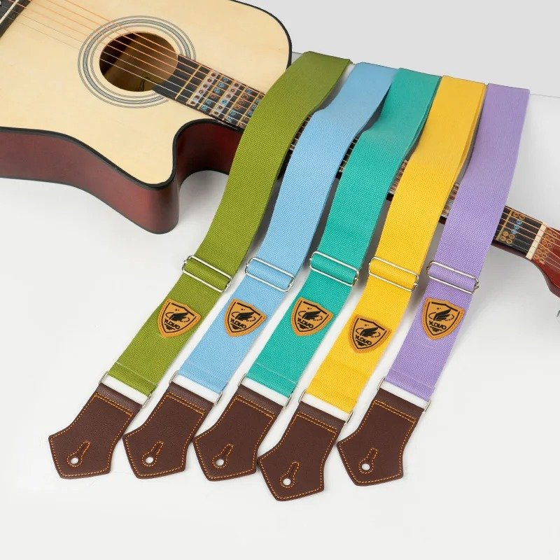 Sangles guitare unies Palette Pop en vert, bleu, turquoise, jaune et violet posées sur une guitare acoustique