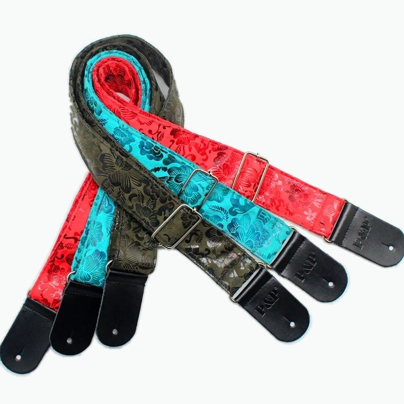 Les 3 coloris de la sangle guitare vintage Wild Flowers à motif floral estampé : rouge, turquoise et kaki Légende : La sangle « Wild Flowers » en 3 coloris.