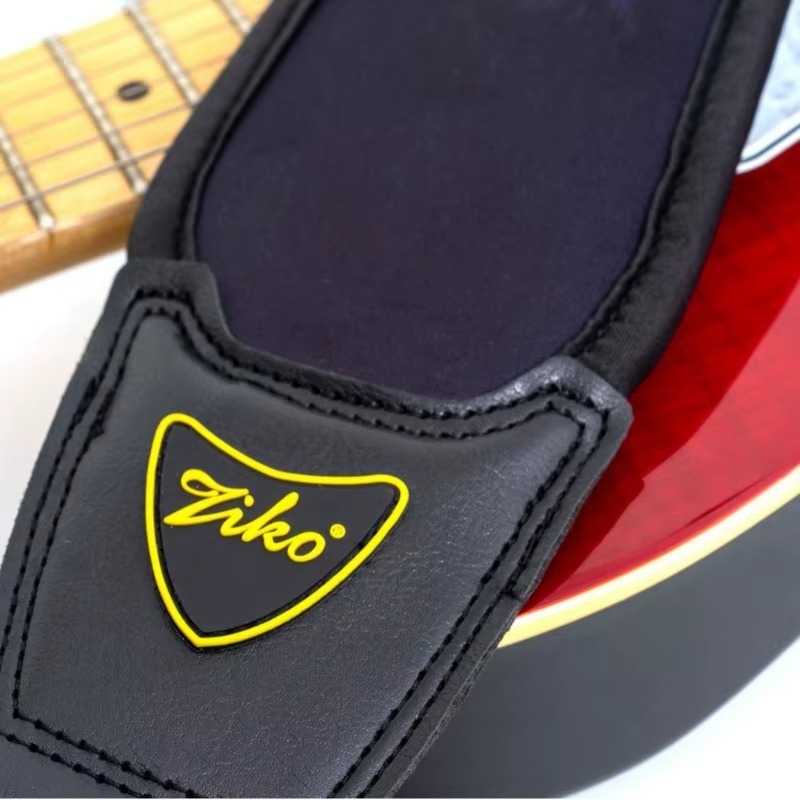 Extrémité en simili cuir surpiqué de la sangle Black Cushion posée sur une guitare électrique